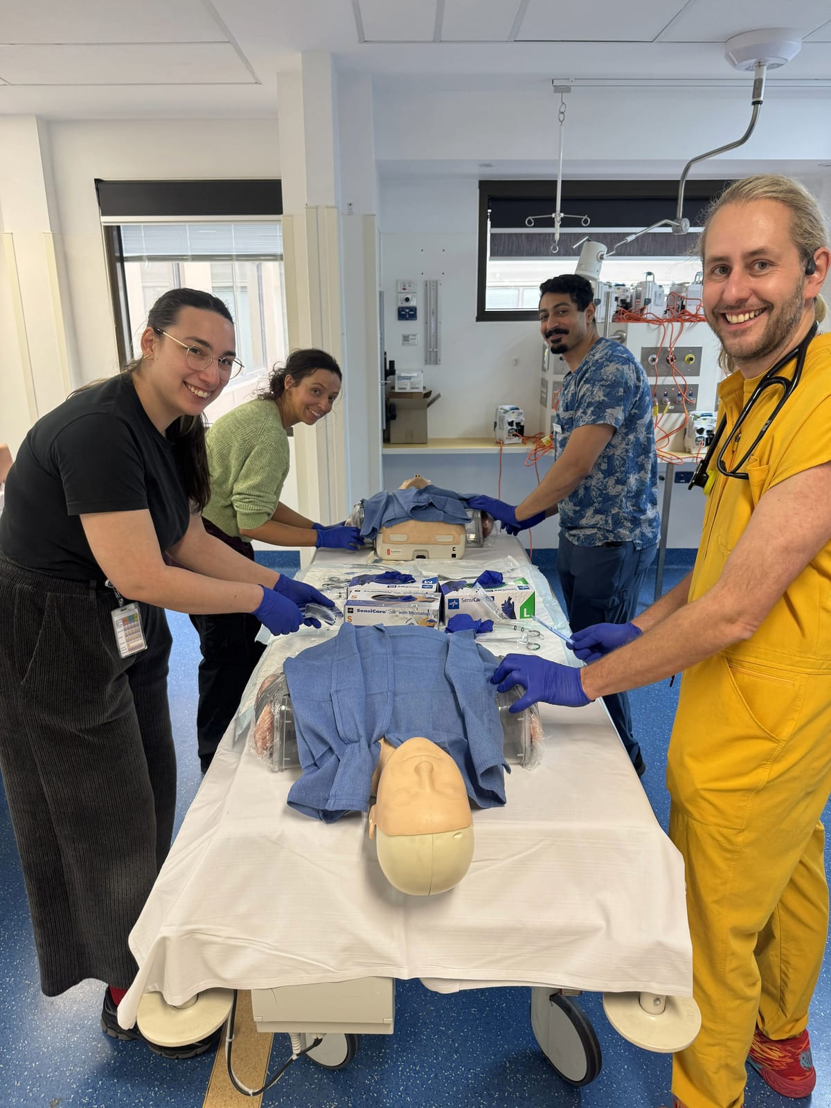 A group of registrars practising a chest tube insertion technique on a training manikin